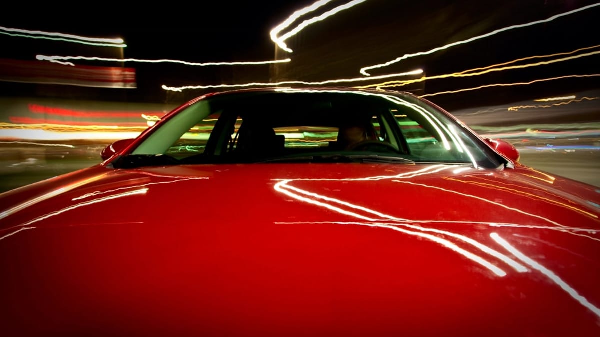 A sports car lit by city lights at night