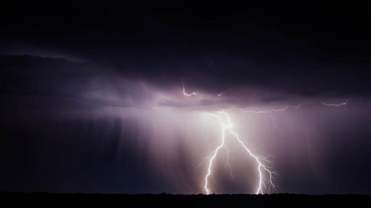 Lightning striking through dark storm clouds at night